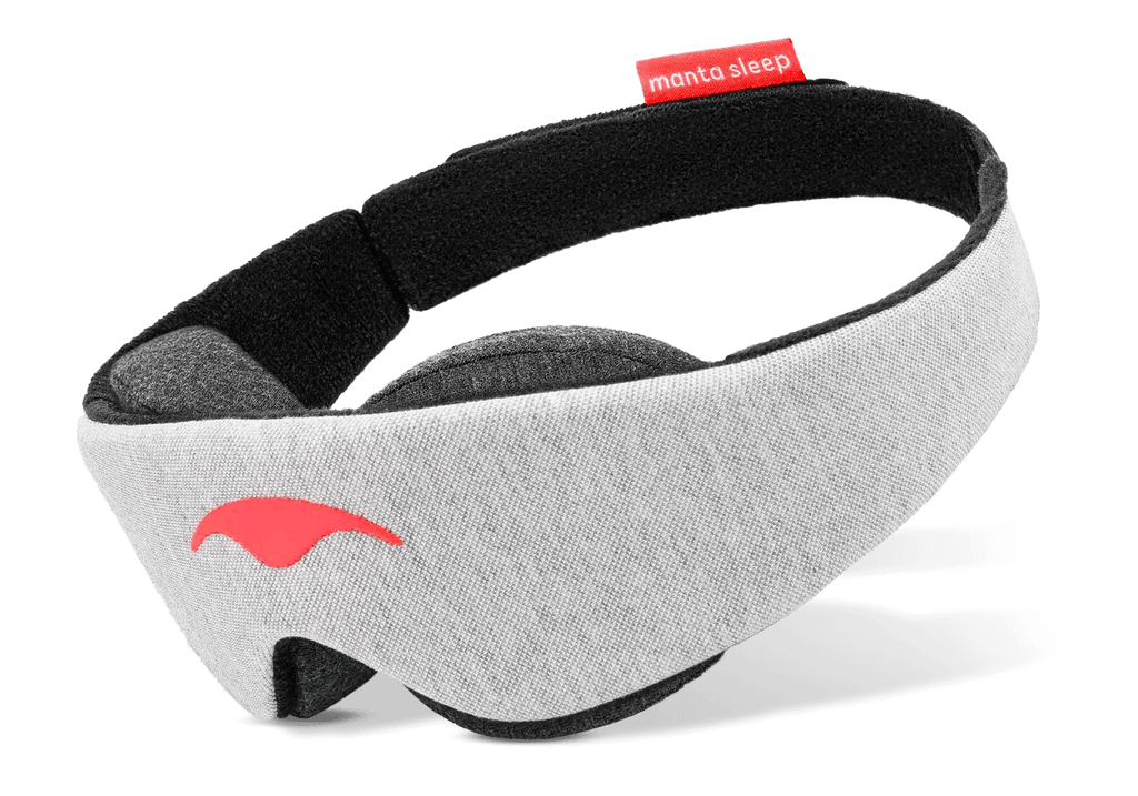 Three-quarter view of a grey Manta Sleep Mask Classic on a white background, featuring a bright red Manta Sleep logo and tag.