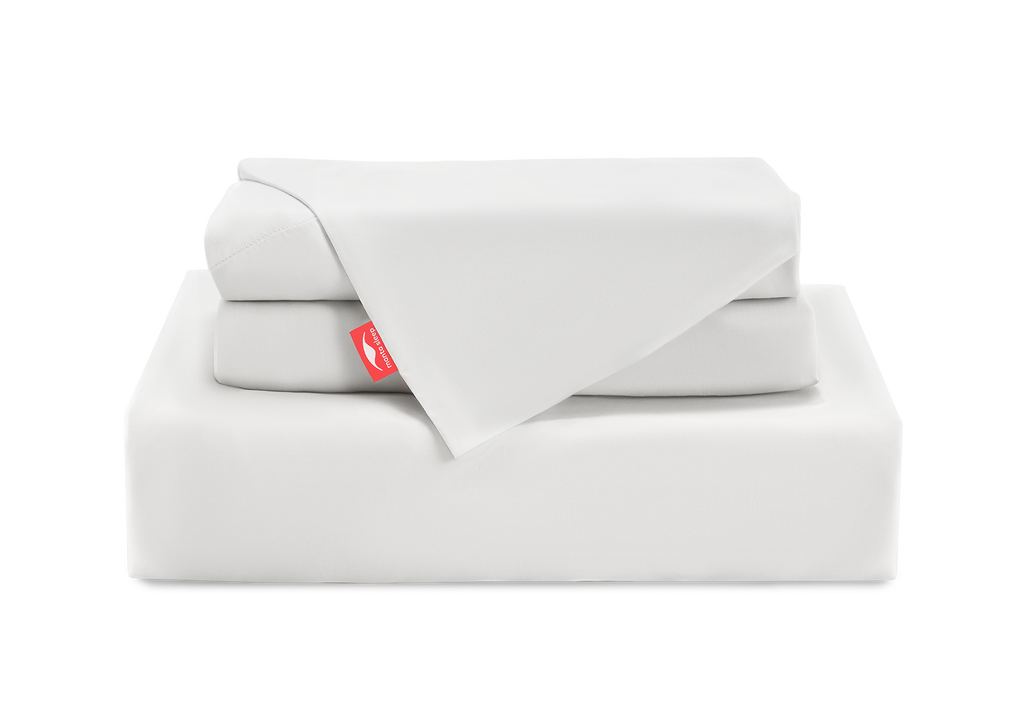 A neat stack of folded white Manta Arctic sheets and pillowcases, featuring a bright red Manta Sleep logo tab, isolated on a white background.