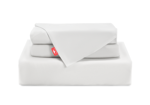 A neat stack of folded white Manta Arctic sheets and pillowcases, featuring a bright red Manta Sleep logo tab, isolated on a white background.