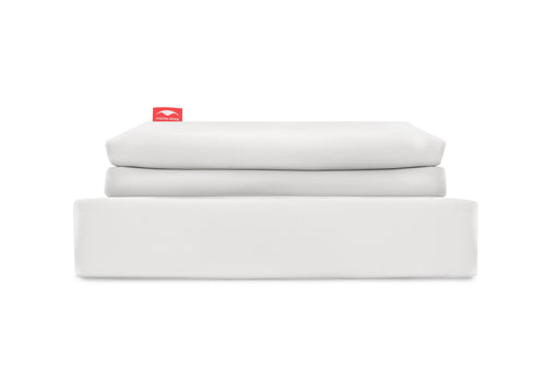 Straight-on studio shot of a white Manta Sleep bedsheet set neatly folded into a clean stack, isolated on a white background.