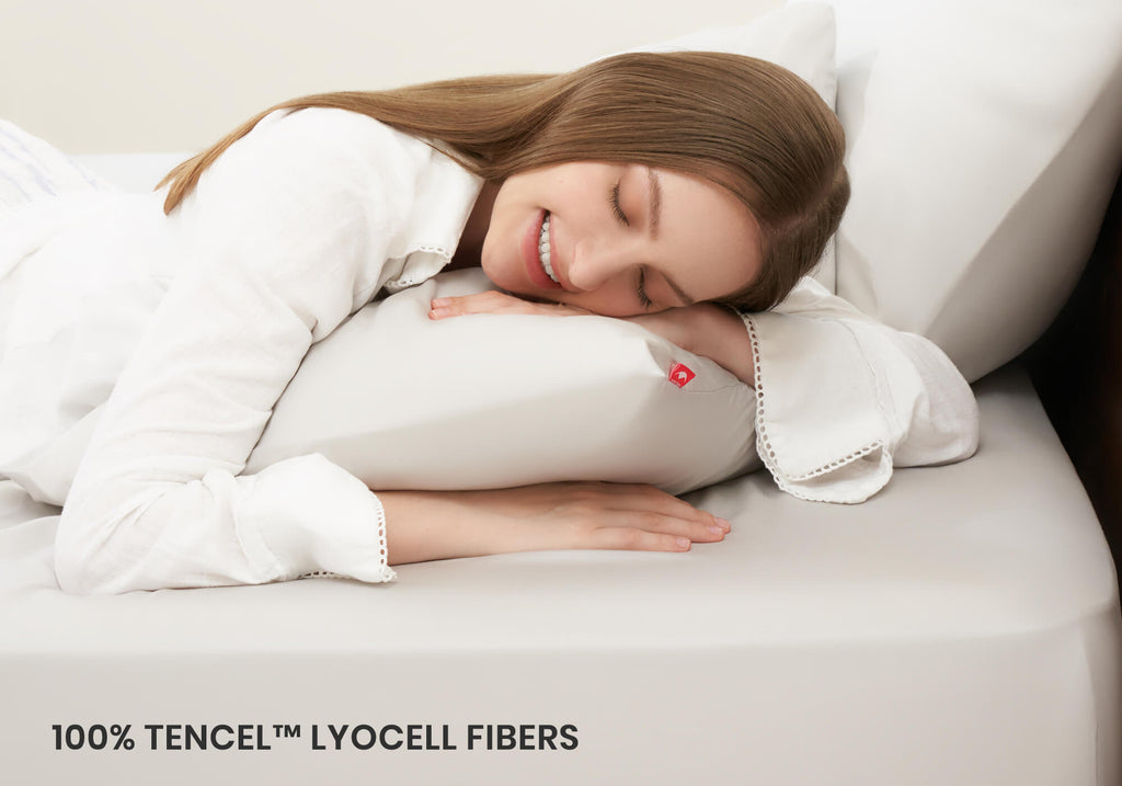 A woman sleeping on her side, hugging a white pillow covered in a Manta Sleep case. Text overlay: "100% Tencel Lyocell fibers".