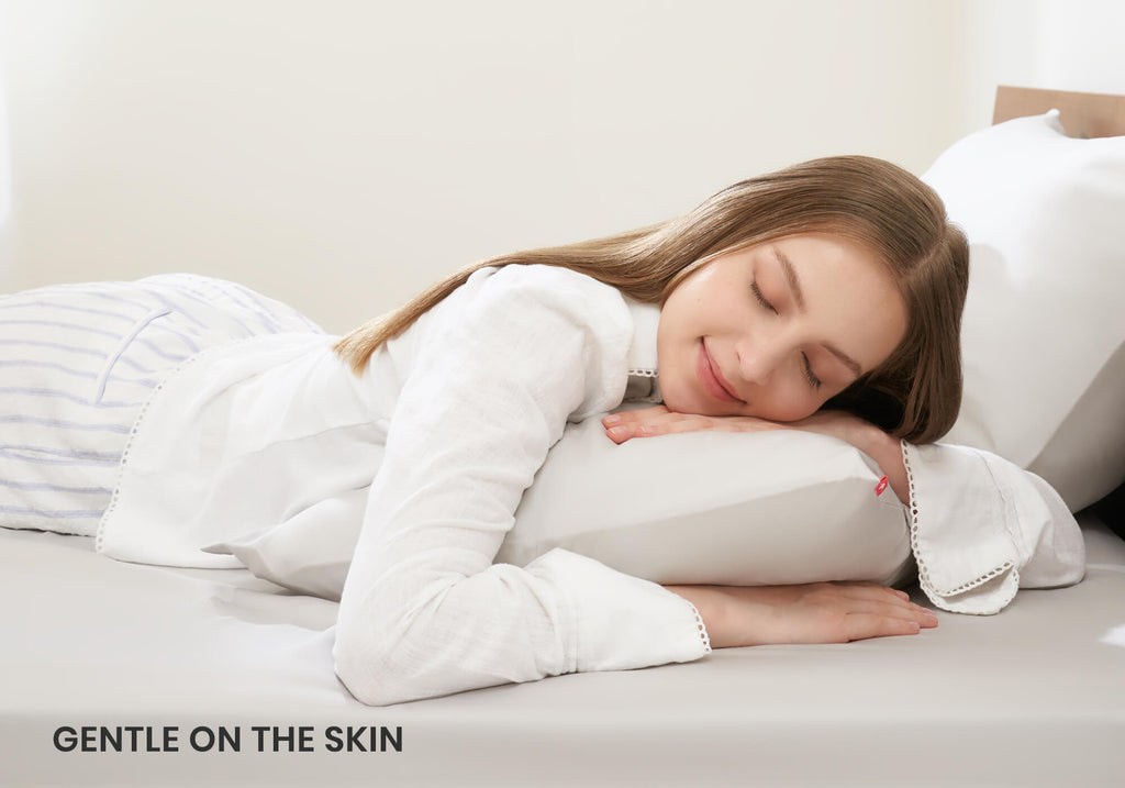 Side view of a woman with long hair resting her head on a white Manta Sleep pillowcase, with text overlay "Gentle on the skin".