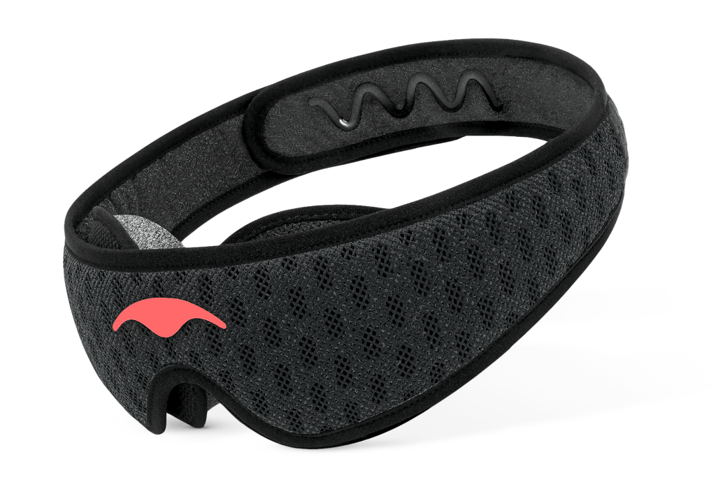Three-quarter studio shot of the Manta Sleep Mask PRO in Carbon Black, displaying the breathable mesh strap and a coral Manta Sleep logo.