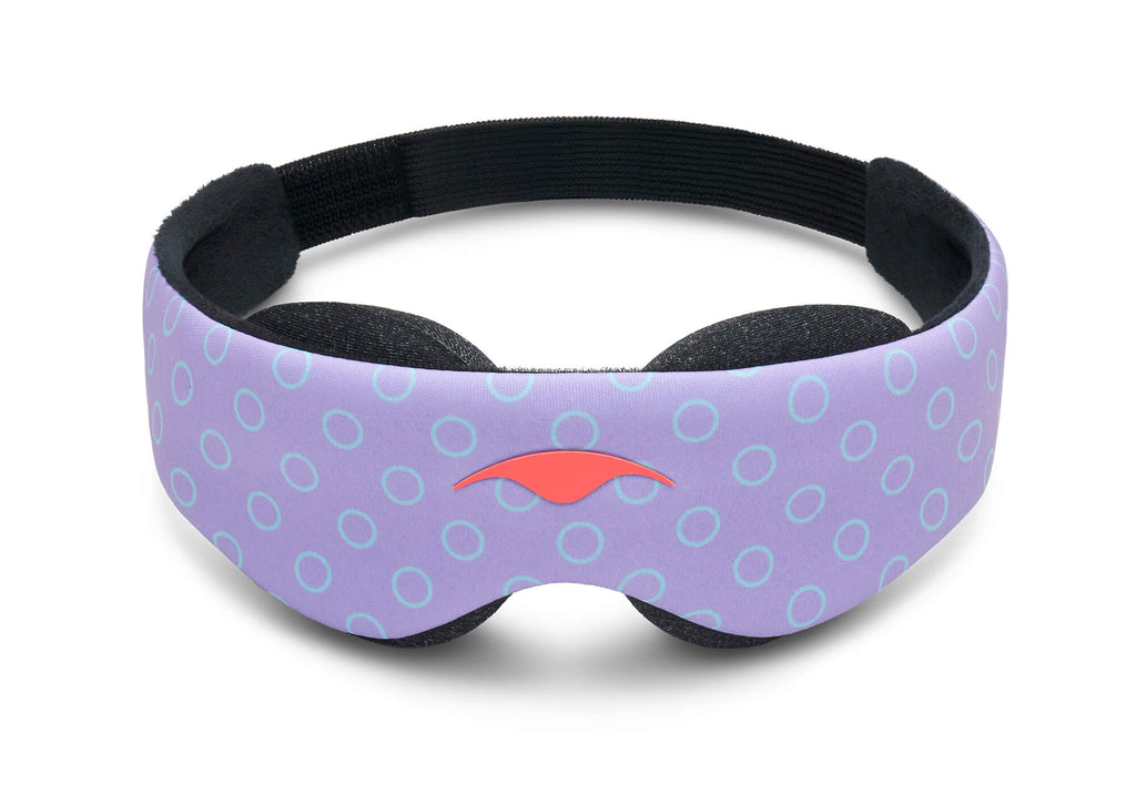 A front-facing product view of the Manta KIDS Sleep Mask standing vertically against a white background. The front panel features a purple base pattern covered in light blue open circles, with a prominent orange Manta Sleep logo centered directly above the nose bridge cutout. The plush black padded eye cups extend slightly below the main body.