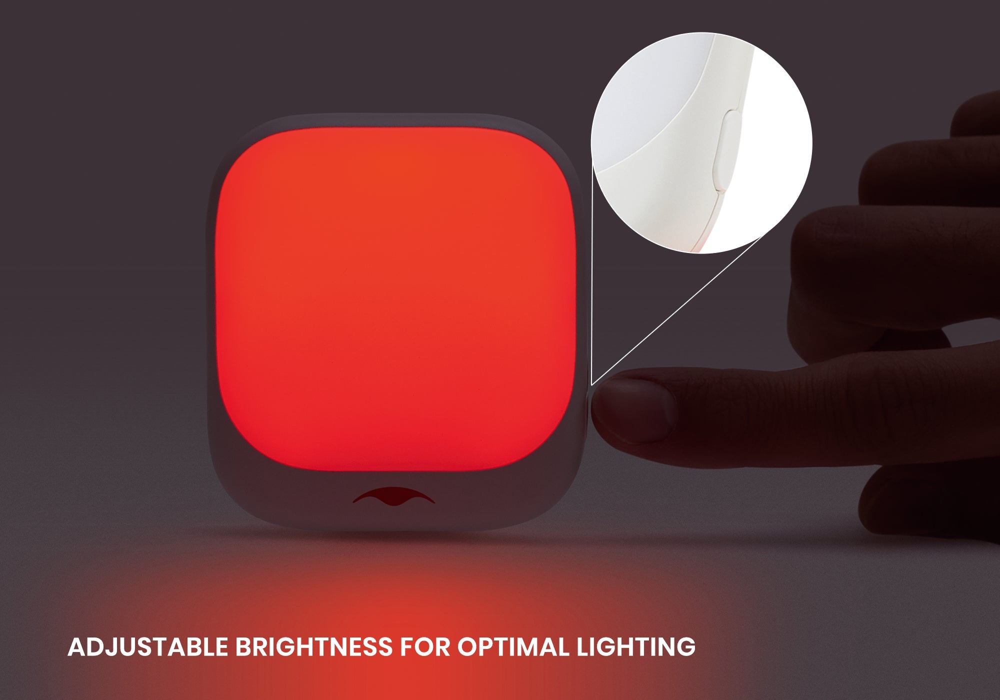 Close-up of a finger pressing the side button of a glowing red Manta Sleep night light, with a magnified view of the button.