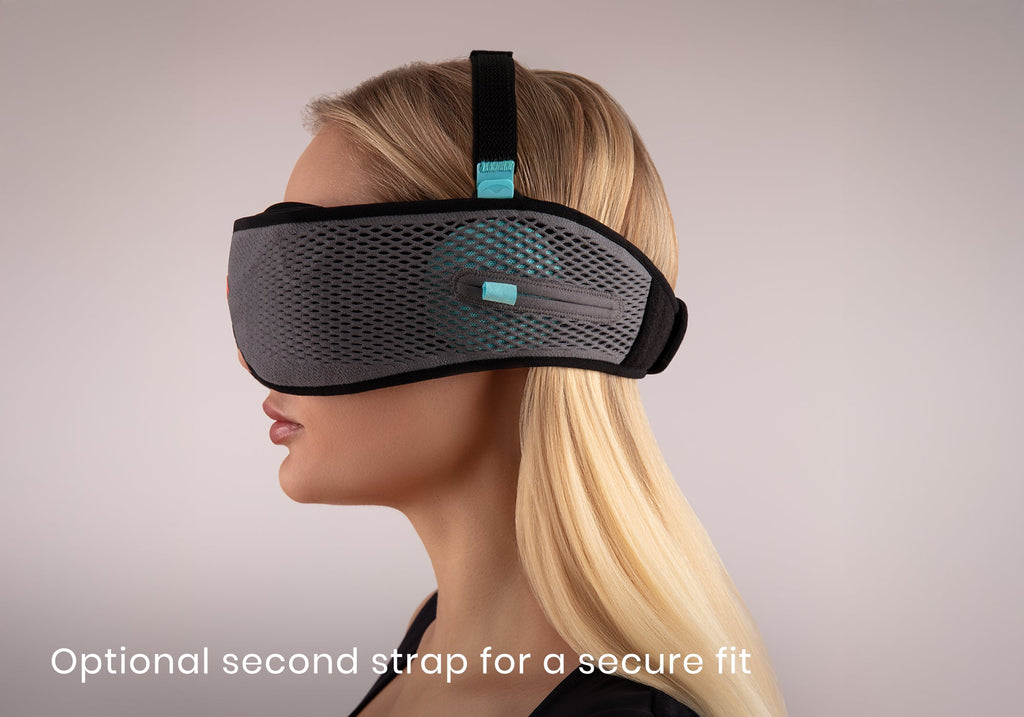 Side profile of a blonde woman wearing a grey mesh sleep mask featuring an adjustable black top strap, captioned "Optional second strap for a secure fit".