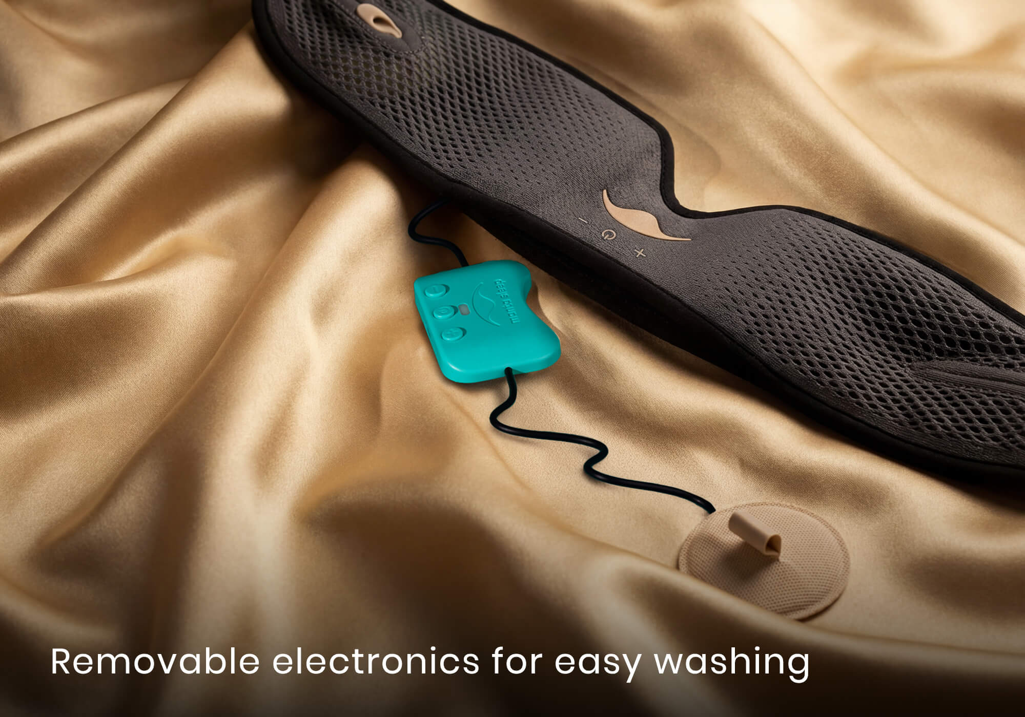 Close-up of a grey mesh mask strap and a detached teal electronic control unit on gold silk fabric. Text: "Removable electronics easy washing".