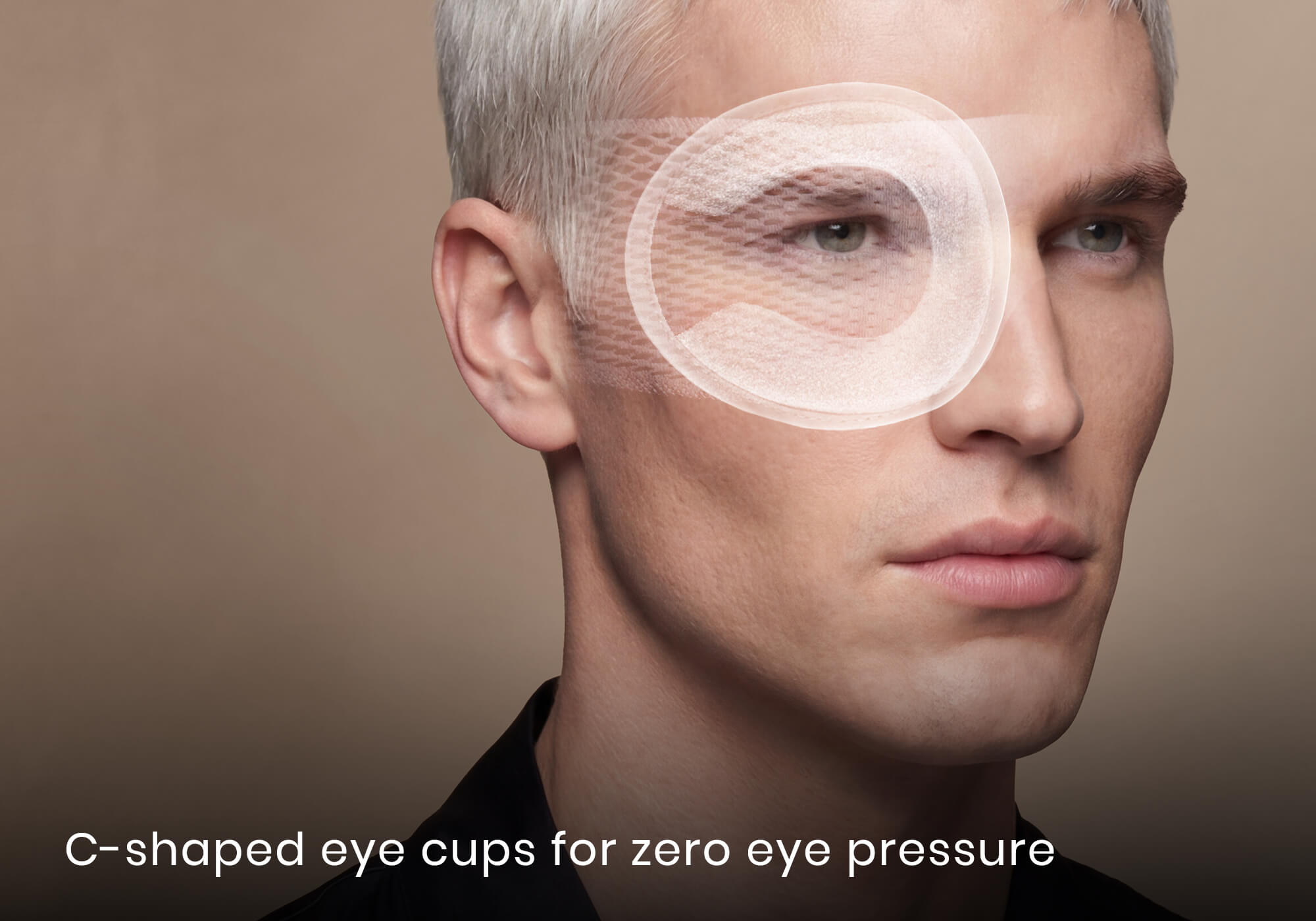 Side profile of a blond man with a white graphic overlay showing a C-shaped eye cup over his eye. Text: "C-shaped eye cups for zero eye pressure".