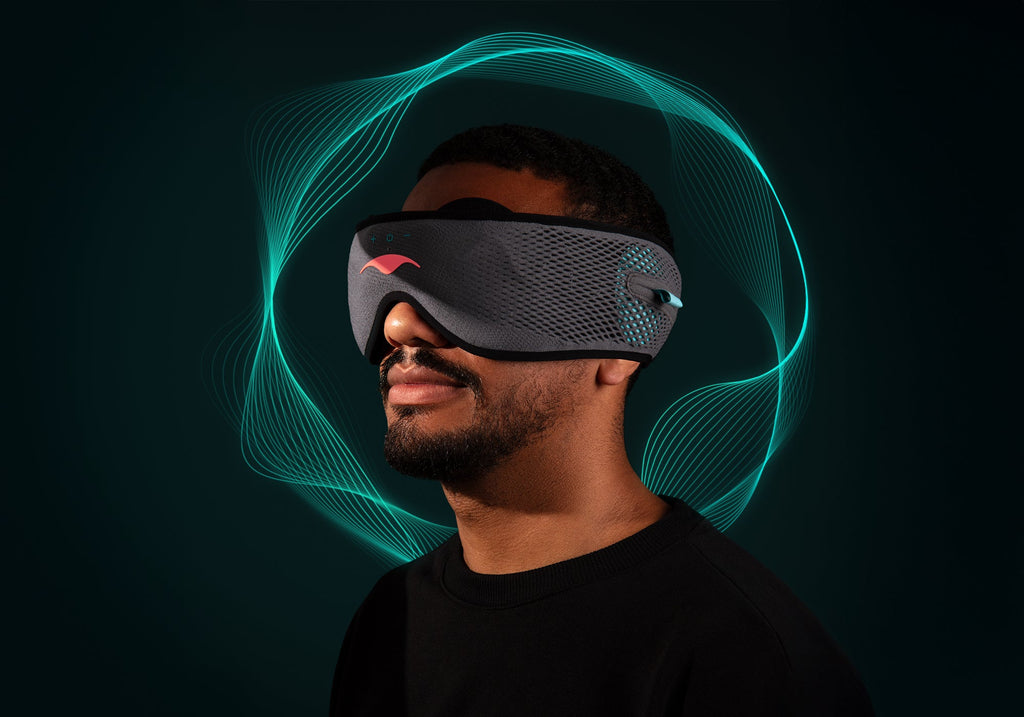 Profile view of a man wearing a grey Manta SOUND Sleep Mask with glowing turquoise soundwaves rippling around his head.