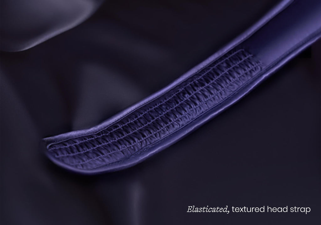 Macro close-up of a glossy, purple silk sleep mask showing detailed ruching, captioned "Elasticated, textured head strap".
