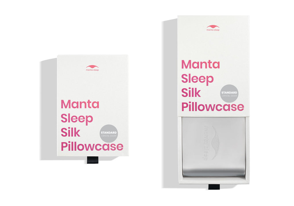 Two white product boxes for the standard crystal silver Manta Sleep silk pillowcase, one closed and one pulled open.