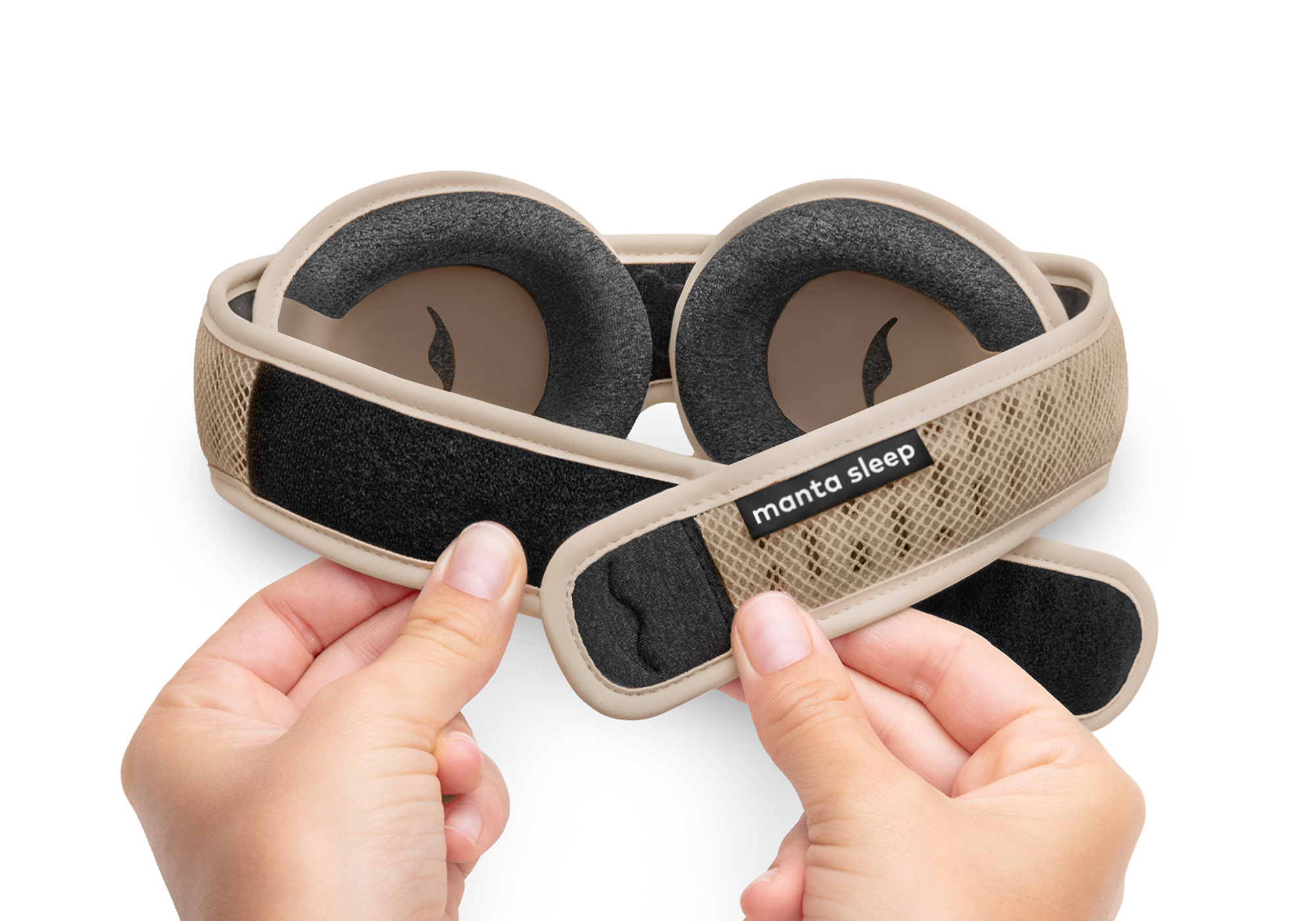 Two hands adjusting the adjustable hook-and-loop closure strap on a light brown Tranquil Taupe Manta PRO Sleep Mask against a white background.