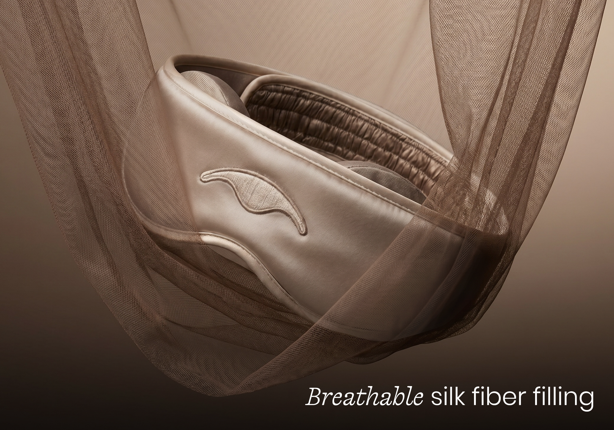 Macro shot of the Tranquil Taupe Manta SILK Sleep Mask nestled in soft folds of matching fabric, captioned "Breathable silk fiber filling".