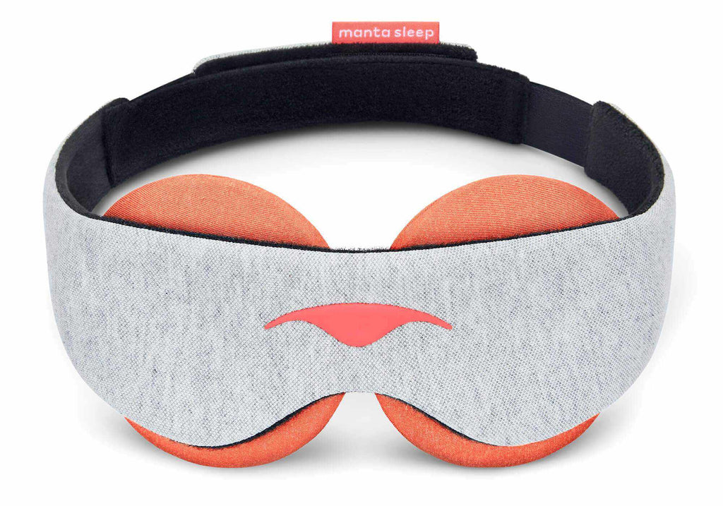 A front-facing vertical view of the Manta STEAM Sleep Mask standing upright against a white background. The mask features a wide, contoured front band made from a soft light gray heathered knit fabric with a coral-red Manta Sleep logo centered near the lower nose bridge cutout. The large, circular terracotta-orange eye cups extend symmetrically above and below the band.