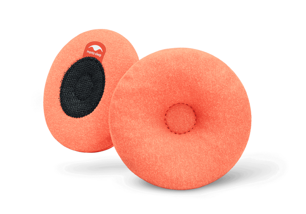 A pair of round orange Manta STEAM Eye Cups, showing the indented front side and the black hook-and-loop back side on white.