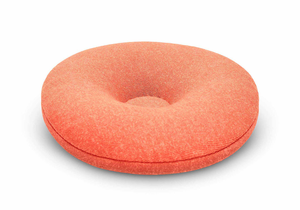 Close-up, angled studio shot of a single circular orange fabric eye cup with a tapered center on a white background.