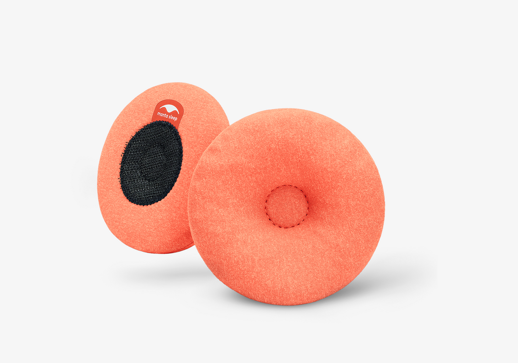A pair of round orange Manta STEAM Eye Cups, showing the indented front side and the black hook-and-loop back side on white.