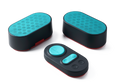 High-angle shot of two oval black white noise speakers with vibrant teal grilles alongside a matching control pad, isolated on a white background.