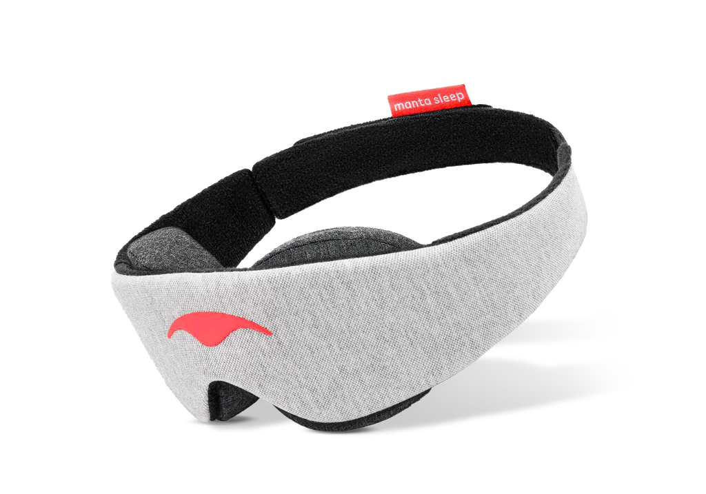 Three-quarter view of a grey Manta Sleep Mask Classic on a white background, featuring a bright red Manta Sleep logo and tag.